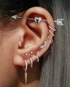 a woman wearing ear piercings with an arrow and heart