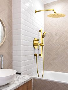 a bathroom with a sink, mirror and shower head in gold fixtures on the wall