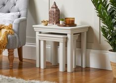 two white tables sitting next to each other on top of a hard wood floored floor