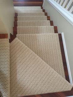 the carpeted stairs are lined with brown and white herringbone rugs, along with wooden handrails