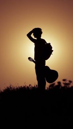 the silhouette of a person holding a guitar