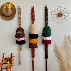 three hats are hanging on the wall next to some flowers and other things in front of them