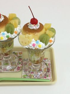 two desserts with fruit and whipped cream in small glasses on a tray next to each other