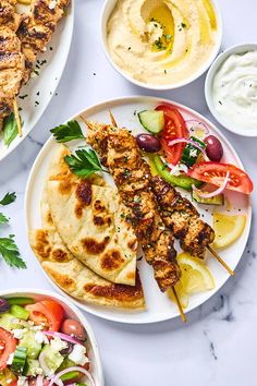 chicken skewers with pita bread, salad and dips on the side