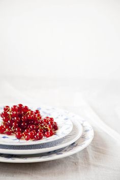 two plates topped with cranberries on top of a white cloth covered tablecloth