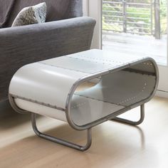 a white bench sitting on top of a hard wood floor next to a gray couch