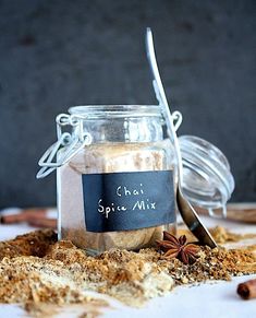 a glass jar filled with spice mix next to a spoon on top of a table