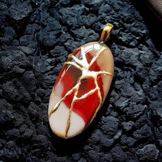 "Welcome to APRAZITA Discover our unique Kintsugi-Inspired Gemstone Jewelry Collection. Kintsugi is a revered Japanese art of mending broken pottery with gold-infused lacquer, transforming flaws into beautiful, valuable features. At APRAZITA, we apply this same process to repair gemstones, infusing them with renewed beauty and significance. Modern kintsugi repairs each gemstone with epoxy paste and gold leaf, symbolizing the beauty in healing life's broken places. Each kintsugi-repaired gemstone is one-of-a-kind due to the process's randomness. The pictured jewelry is the one you'll receive. Take a closer look at each image to fully appreciate the distinctive intricacies of this remarkable gemstone. Our dedication to merging gemstones with other art forms is truly exceptional. 🔹 ITEM DETA Handmade Oval Glass Necklace, Elegant Glass Rectangular Pendant Jewelry, Minimalist Glass Jewelry For Gifts, Elegant Necklace With Artistic Round Pendant, Minimalist Glass Jewelry Perfect For Gifts, White Fusion Style Necklace For Gift, Red Large Pendant Jewelry For Gift, Artistic Gold Jewelry With Cabochon, Artisan Heart Pendant Necklace As Gift