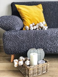 a blue couch sitting next to a yellow pillow on top of a wooden floor