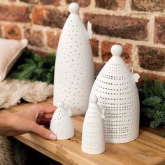 three white ceramic vases sitting on top of a wooden table next to a brick wall