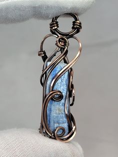 This listing is for an oxidized copper pendant created by me, in my 'Tyet' style.  The crystal is a raw Blue Kyanite crystal from Brazil. Dimensions: 53mm x 12mm x 10mm Weight: 9 grams This pendant comes ready to wear with a free chain and polishing cloth.  The photos are of the item you will receive. Please note the size of the item featuring a US Quarter for reference. Thanks for looking! Blue Kyanite Crystal, Kyanite Crystal, Wire Wrapped Jewelry Tutorials, Bijoux Fil Aluminium, Wire Wrap Pendant, Oxidized Copper, Copper Pendant, Blue Kyanite, Copper Pendants