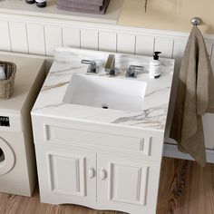 a white sink sitting next to a washer and dryer in a bathroom on top of a wooden floor