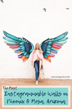 a woman standing in front of a white wall with colorful wings