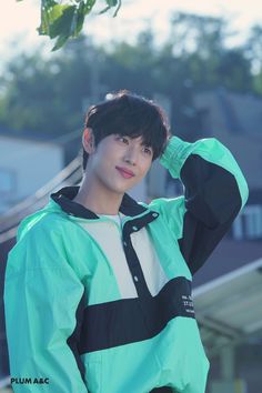 a young man in a green and black jacket is posing for the camera with his hand on his head