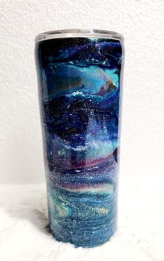 a blue and purple tumbler cup sitting on top of a white countertop next to a wall