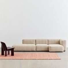 a living room with a couch, chair and rug on the floor in front of a white wall