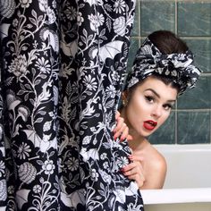 a woman in a black and white dress is standing next to a bathtub with a shower curtain