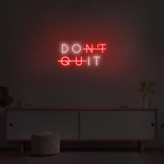 a red neon sign that says don't quit on the side of a wall