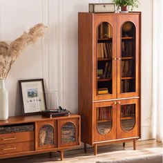 a wooden bookcase sitting next to a vase filled with flowers