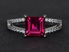 a pink tourmaline and diamond ring on a black surface with diamonds around it