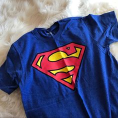 Blue Superman T Shirt With Logo Printed On The Front, Never Worn And Excellent Condition! Blue Pop Culture T-shirt With Character Print, Casual Blue Shirt With Character Print, Blue Superhero T-shirt With Character Print, Blue Superhero Short Sleeve Top, Blue Short Sleeve Superhero Tops, Superhero Screen Print Crew Neck Top, Superhero Crew Neck Top With Screen Print, Blue Superhero Crew Neck Top, Superhero Cartoon Print Crew Neck Top