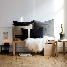 a couch with some pillows on top of it next to two tables and a potted plant