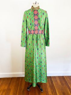 Funkadelic 1970s Emilio Borghese novelty print embroidered printed maxi dress. Mock neckline,  long sleeves, darted buts, nipped at the waist, and slightly flared a-line maxi skirt. Made of light weight polyester knit fabric in green with printed embroidered pattern in pink, purple, and orange. Unlined, back nylon zipper. Label: Emilio Borghese Roma, 100% polyester, circa 1970s. In wonderful vintage condition, one small repair at the bust done by previous owner (un-seen when worn, seen in detail Retro Green Dress With Vintage Print, Retro Long Sleeve Festival Dresses, Retro Green Long Sleeve Maxi Dress, Retro Long Sleeve Dresses For Festival, Green Long Sleeve Retro Maxi Dress, Retro Green Dress With Vibrant Print, Vintage Green Embroidered Dress, Vintage Embroidered Green Dress, Green Embroidered Vintage Dress