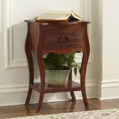 a small wooden table with a potted plant on it and a book on top