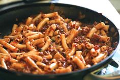 a skillet filled with pasta and sauce on top of a stove