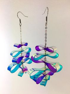 a pair of earrings hanging from chains with blue and purple glass pieces attached to them