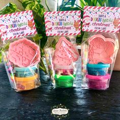 three plastic containers filled with different colored wax pastes and some plants in the background