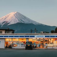 a truck parked in front of a building with a mountain behind it's roof