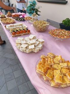 a table topped with lots of food on top of a pink tablecloth covered table