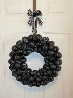 a wreath hanging on the front door of a house decorated with black baubles