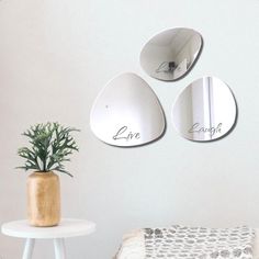 three mirrors hanging on the wall above a small table with a potted plant in it