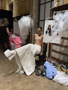 a man sitting on top of a chair next to a pile of clothes and other items