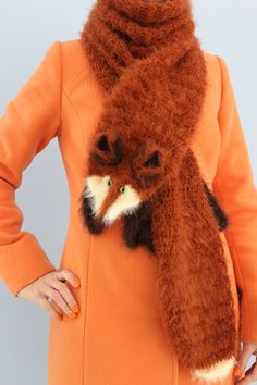 a woman wearing an orange coat with a fox scarf around her neck and hands on her hips