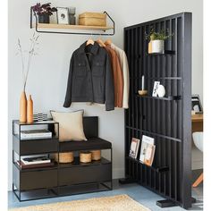 a coat rack with clothes hanging on it next to a chair and shelf filled with books