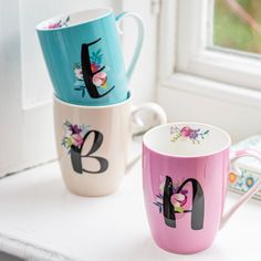 two coffee mugs sitting on top of a window sill next to each other