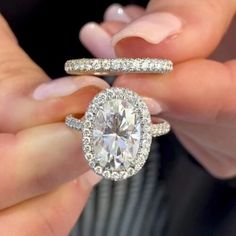 a person holding an engagement ring and wedding band with a diamond in the middle on their fingers