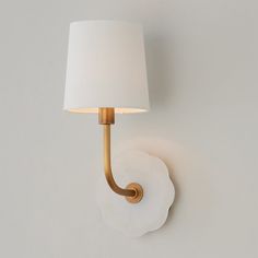 a wall light with a white shade on it's side and a gold arm