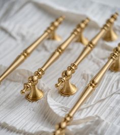 six brass bell finial handles on a white fabric covered tablecloth, all lined up and ready to be used