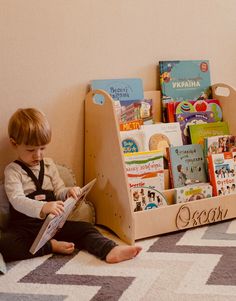 a young boy sitting on the floor reading a book