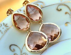 two gold tone earrings with large brown stones on it's earwires, sitting on a white plate