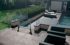 an outdoor swimming pool with lounge chairs next to it and a green wall in the background