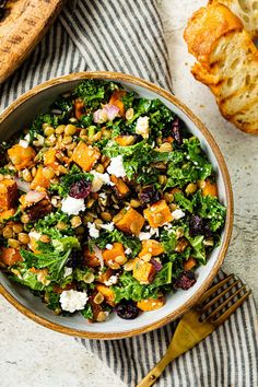 a bowl filled with salad next to bread