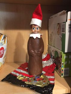 an elf is sitting on top of a chocolate candy bar in the closet with other items