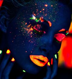 a woman's face is covered in bright fluorescent powder and has glowing makeup on her face