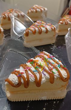 several desserts with icing and sprinkles are on plastic trays