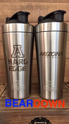 two stainless steel coffee mugs sitting next to each other on a wooden table with the words arizona hard edge above them